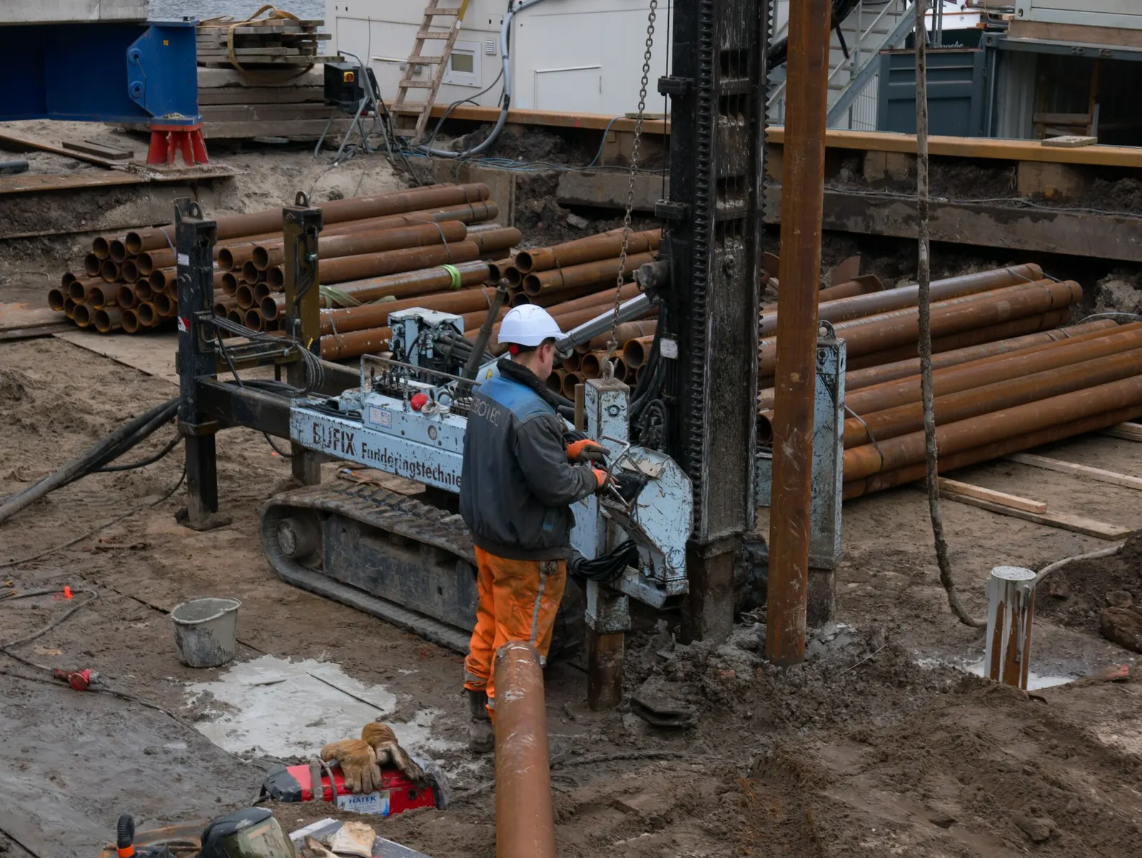 Construction worker drilling foundation piles on site