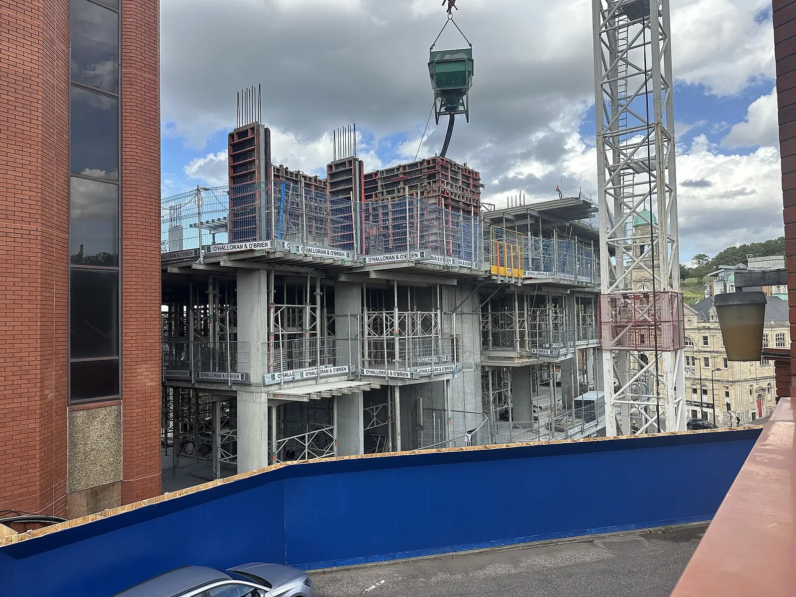 Mid-rise concrete building under construction with a tower crane